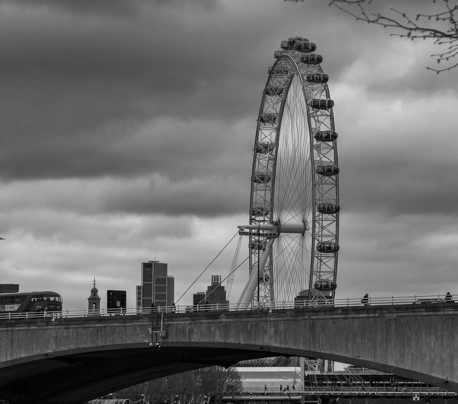 London Eye ferris wheel with cloudy sky and bridge in black and white.