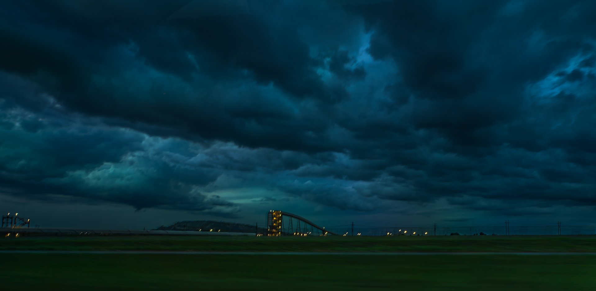 Dramatic stormy sky with dark clouds over an industrial landscape at dusk.